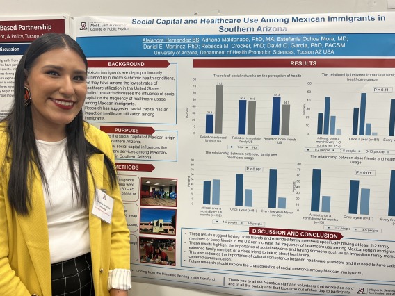 student standing in front of research poster