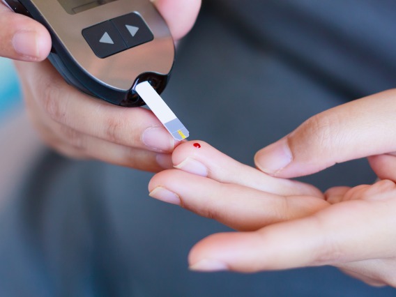 hands using a glucose monitor to test a drop of blood