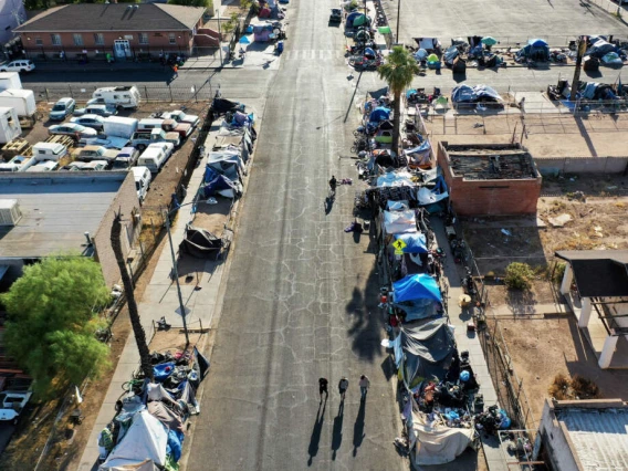 In an aerial view, people walk through a section of the 'The Zone', Phoenix's largest homeless encampment
