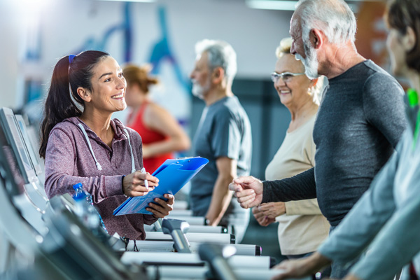 Trainer in gym with older people on treadmill