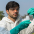 technician in overall protective suit collecting samples of soil